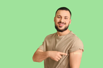 Young man with applied medical patch on green background. Immunization concept