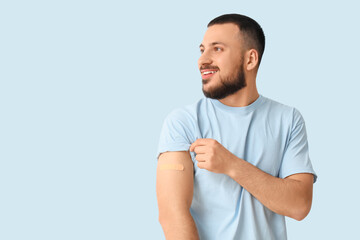 Young man with applied medical patch on blue background. Immunization concept