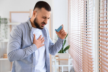 Young man with inhaler having asthma attack at home