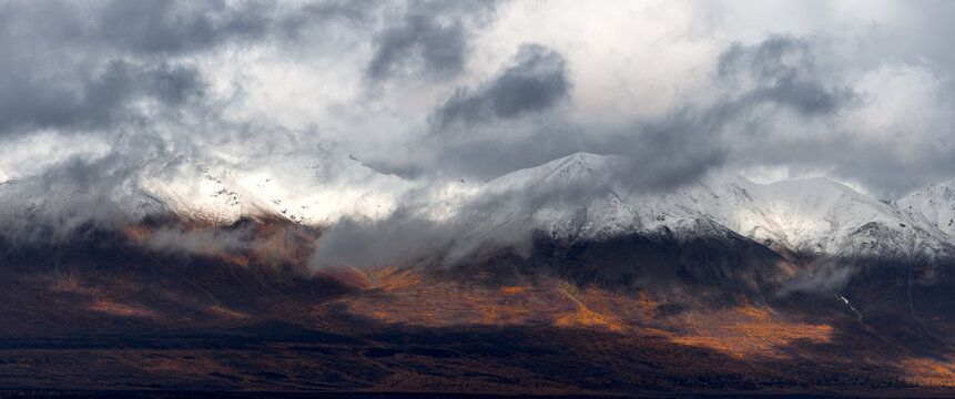 Panoramic view of snow covered mountains with dense low level clouds in Alaska during autumn time.