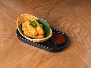 Deep fried cheese sticks in basket with dipping sauce on wooden table
