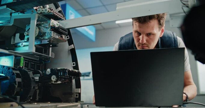 Technician Servicing ATM Machine in Airport Terminal. Man in Uniform Inspecting Internal Components of Automated Teller Machine Using Laptop. Banking Services, Cash Withdrawal Systems. Dolly Shot.