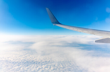 View from the airplane window at a beautiful cloudy sky and the airplane wing