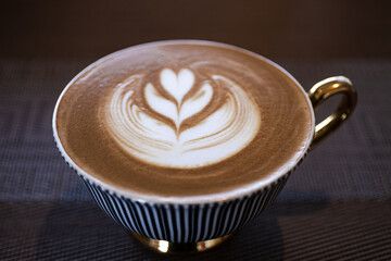 latte art in elegant ceramic cup with golden handle