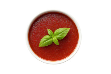 Fresh tomato soup with basil garnish in white bowl on black background, cut out