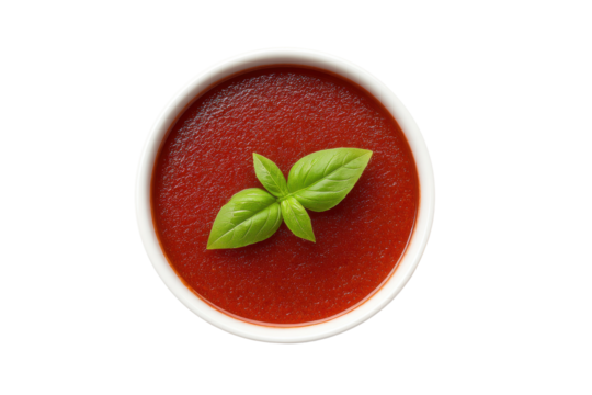 Fresh tomato soup with basil garnish in white bowl on black background, cut out