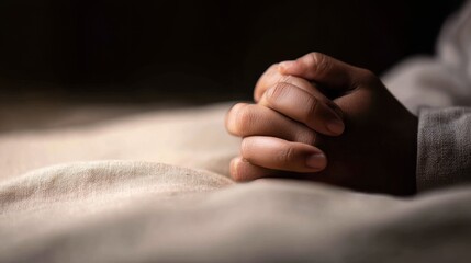 Obraz premium Close-up of clasped hands resting on a soft surface, conveying calmness and reflection