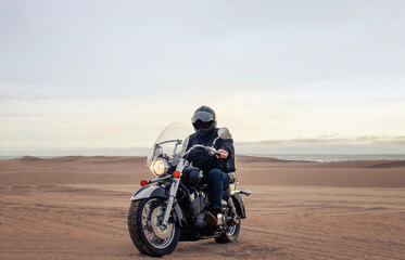 Man on motorcycle in desert during sunset with dramatic clouds — concept of freedom, travel, solitude, adventure, and outdoor lifestyle in wild open landscapes