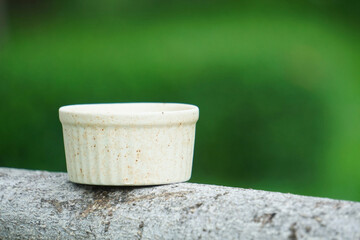 Ceramic cup placed in the garden with a green grass background. Can be used as an illustration to add additional objects.