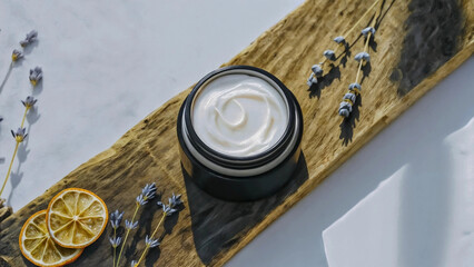 Jar of cream on wooden board with lavender and dried citrus isolated on white background