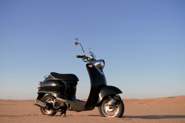Stylish black retro scooter in the Namib Desert at sunset. Perfect for travel, adventure, freedom,...