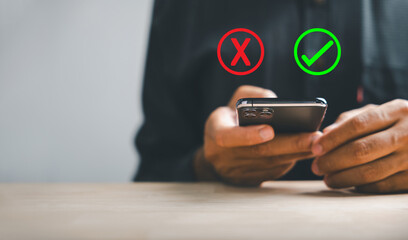 Smartphones aid businessman in showing right and wrong icons for yes or no decision. Communication of choice progress and success. Think With Yes Or No Choice.