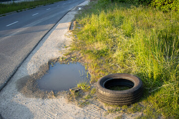 A used tire lying on the asphalt road, highlighting the importance of tires in vehicle safety,...