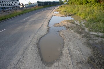 A puddle near the asphalt road in the light of the setting sun.