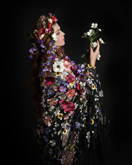 Studio Portraits of Female Model as Celtic Spring Goddess, Floral Fantasy Costume, Inspired by Beltane Pagan Mythology, posing facing away, looking backwards. isolated Dark studio Background