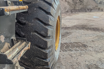 Close-up of a large construction vehicle tire with visible treads and dirt, captured at a dusty...