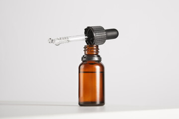 Black cap with pipette lies on open brown glass bottle.