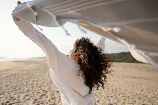 Person enjoying a breezy day at the beach with a cloth in hand