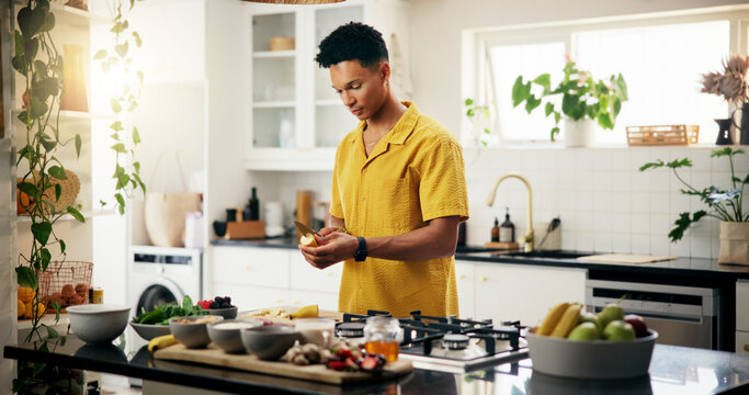 Banana, cooking and concentration with man in kitchen of home for hobby, meal prep or nutrition. Ingredients, peeling and recipe with person in apartment for diet, health or supper as culinary chef - Powered by Adobe