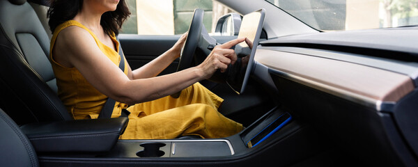 Mature woman using digital tablet while driving electric car