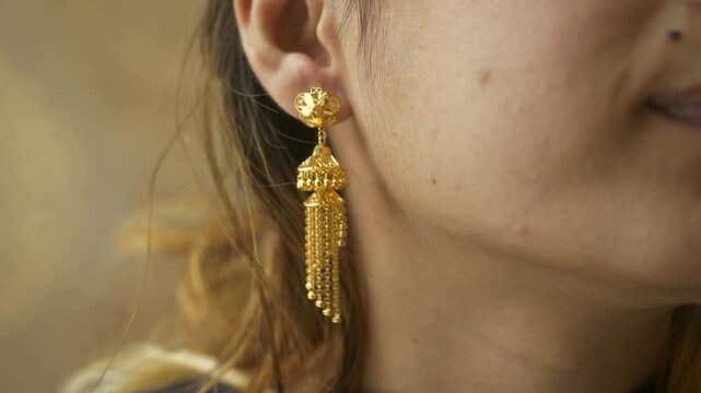 Young asian woman wearing designer 18k HUID certified gold earrings, Closeup of ear