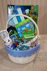 Naklejka premium San Diego, CA USA on April 18, 2025. Homemade Easter basket idea for boys. Easter basket filled with toys, candy, money and t-shirt.