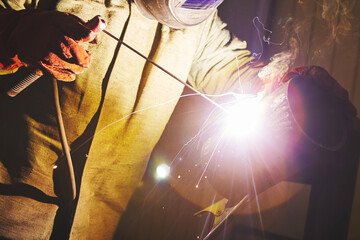 Portrait of worker in protective mask welds metal.