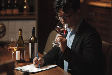 Sommelier Writing on Paper While Holding Glass of Wine