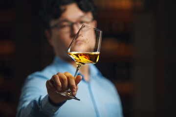 Sommelier Intently Evaluating Color and Transparency of White Wine in Glass
