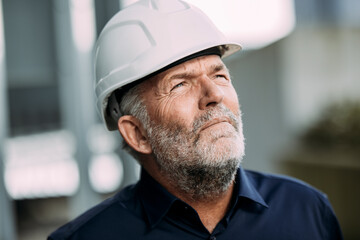 Engineer in a hard hat looking up outdoors, symbolizing expertise and success
