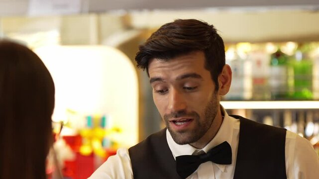 Good looking smiling smart bartender friendly conversation talking VIP customer woman at beverage bar while recommending drink list making great first impression in neat professional barman. Vinosity.