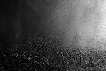 close-up of textured black metallic surface with rough and smooth sections showing varying shades and highlights