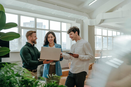 Colleagues discussing work on a laptop in a modern office