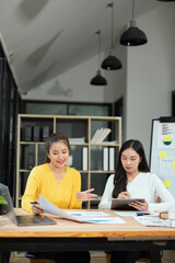 Two professional business executives working on laptop computer sitting at office desk, happy colleagues discussing company digital strategy.
