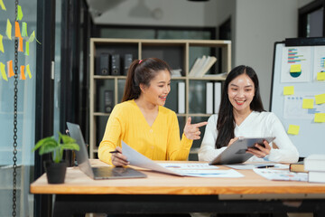 
Two professional business executives working on laptop computer sitting at office desk, happy colleagues discussing company digital strategy.
