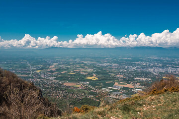 Vue panoramique spectaculaire du bassin genevois depuis le Salève, révélant la ville de Genève, le lac Léman et les montagnes environnantes sous une lumière naturelle et dégagée.