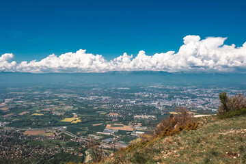 Vue panoramique spectaculaire du bassin genevois depuis le Salève, révélant la ville de Genève, le lac Léman et les montagnes environnantes sous une lumière naturelle et dégagée.