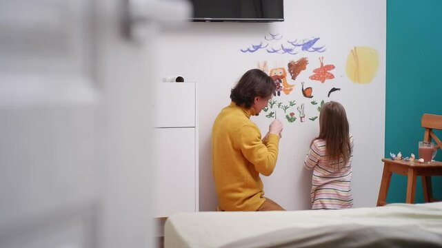 Dad and daughter enjoy quality time painting a mural on a bedroom wall