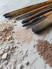 Close-up of various makeup brushes and powders arranged artistically on a marble surface