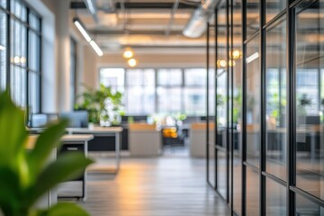 Fototapeta premium Contemporary office interior with blurred backgrounds, showcasing workstations and greenery in a bright environment