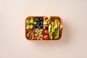 A lunch box containing fresh fruits, vegetables, nuts, and sandwiches arranged neatly