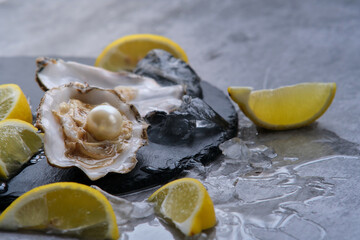 Oyster with pearl and lemons on a gray background
