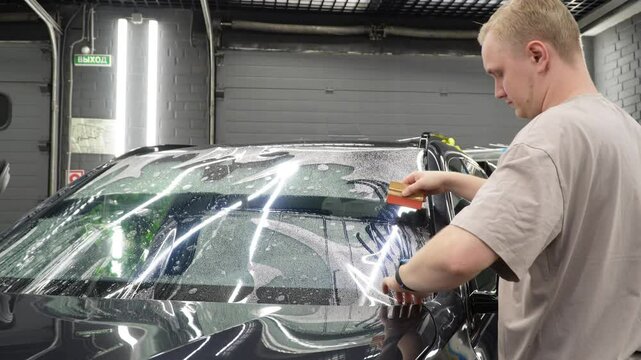 The process of installing the protection film on the windshield of a car. PPF is a paint protection film that protects paint from scratches and gravel. Athermal film on the windshield of the car.