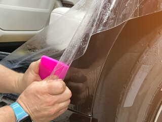 A car wrapping specialist applies a polyurethane film to the car. Selective focus. PPF protective...