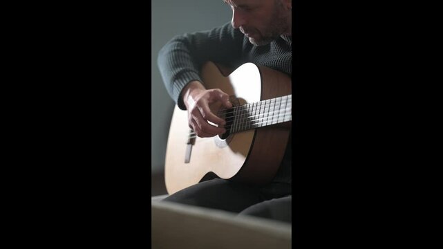 Musician playing acoustic guitar at home