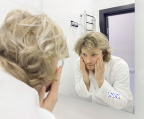 morning routine, young man looking in mirror in bathroom
