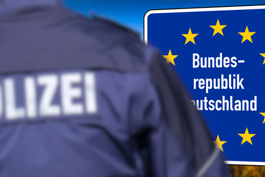 Ein Polizist steht an der deutschen Grenze vor dem Schild Bundesrepublik Deutschland