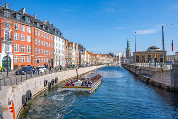 Tourists enjoy a sunny boat ride along Frederiksholms Kanal, surrounded by historic buildings and vibrant architecture in the heart of Copenhagen, Denmark.