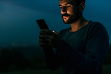 Young man using smartphone at night in nature
