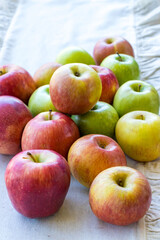 Apples of different varieties such as Granny Smith, Starking, Fuji are on the table